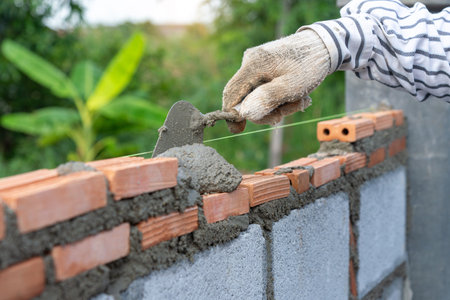 Masonry worker make concrete wall by cement block and plaster at construction site.の写真素材