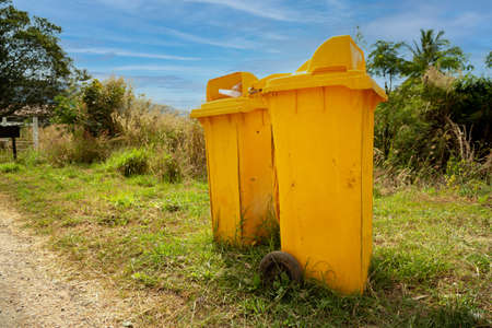 Yellow trash cans are located in the park.の写真素材