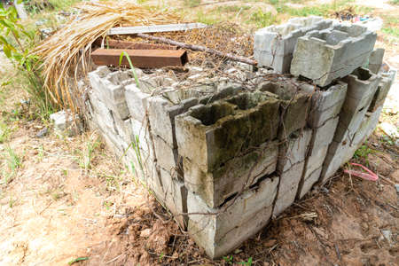Old cinder blocks of gray concrete are neatly stacked in a pile, slender rows of bricks, material...