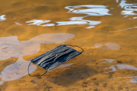 Coronavirus Plastic Waste Polluting the Environment. Discarded used disposable medical mask floats...
