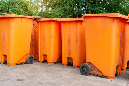 Orange rubbish bin in a public place. essential equipment to keep the environment clean and comfortable, Orange Plastic Waste Container Or Wheelie Bin.の写真素材