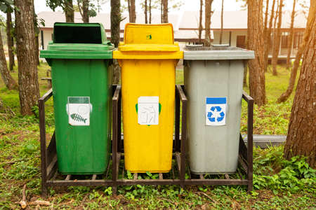 Trash bin located in the public park. Three containers of different colors for collecting different types of garbage are on the ground in public garden, Concept environmental stewardship.の写真素材