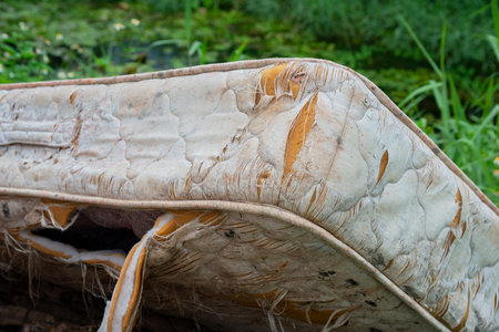 Close-up   Old mattress on the grass,  cement floor, Forgotten, rusty, dirty torn old Mattress, Old discarded mattress on the street.の写真素材