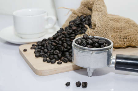 black roasted arabica coffee beans and cup full of coffeeの写真素材