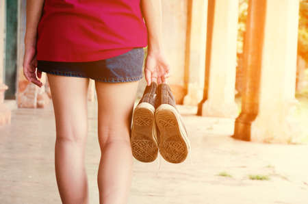 sneakers on hand woman.Outdoor lifestyle close-up of the legs of black beautiful teenage girl.の写真素材