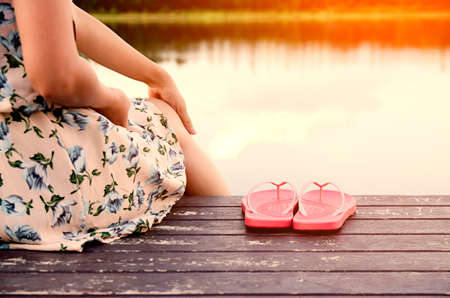 Close up young woman sit wooden floor with slippers on the river.young woman sit solitary a near riverの写真素材