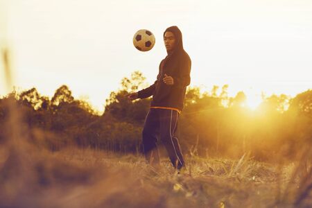 Soccer player in action on sunset with field in the countrysudeの写真素材