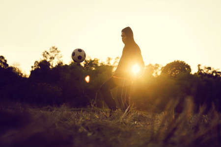 Soccer player in action on sunset with field in the countrysude