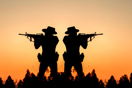 Asian two military silhouettes on sunset sky backgroundの写真素材