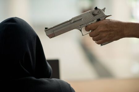 close up human hand holding gun threaten hacker for damage in security network.の写真素材