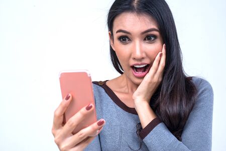 Beautiful asian woman has attractive appealing appearance and shocked expression on smart phone,...