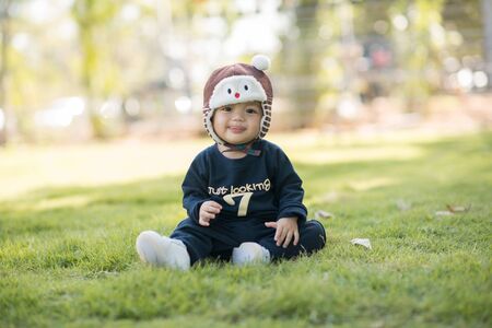 Cute asian little boy sitting in the grass outside