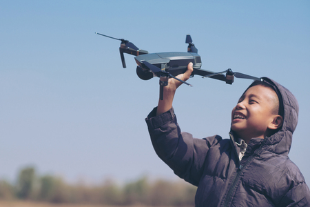 Cute boy holding drone at meadow, Child playing with drone outdoors at summer dayの写真素材