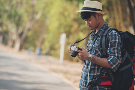 Hiking man using camera with a vintage camera and hat,backpack relaxing outdoor on background Summer vacations and Lifestyle hiking concept.の写真素材