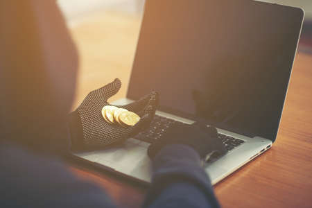 closeup photo of male hacker counting bitcoin when he using computer hacking online system. holding gun on handの写真素材