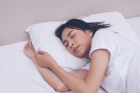 Young woman sleeping on white pillow in bedroomの写真素材