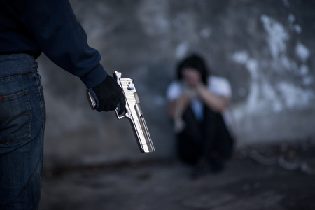 Close up man holding a gun.Sexual harassment , stop violence against Women, international women's day,Helpless young woman hands tied with rope, Missing kidnapped, Hostage, human trafficking and violence conceptの写真素材