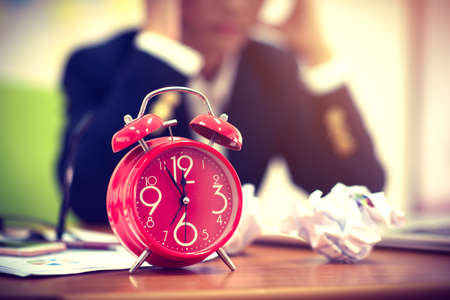 Alarm clock with blurred background of businesswoman work until coffee break, Sad jobの写真素材