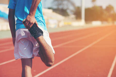 young fitness young man runner stretching legs before run on cityの写真素材