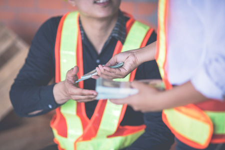 foreman worker and engineer meeting for sign contract and profit from construction on a construction site relaxing and holding moneyの写真素材