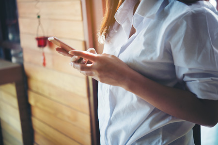 Happy beautiful Asian woman looking at mobile phone display at coffee shopの写真素材