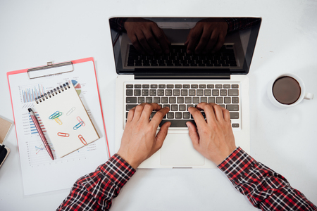 Close up young man working and smart phone and laptop on wooden desk in officeの写真素材