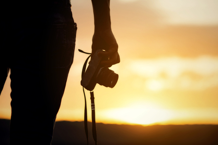 Backpacker relax on the Mountain with camera adn sunsetの写真素材