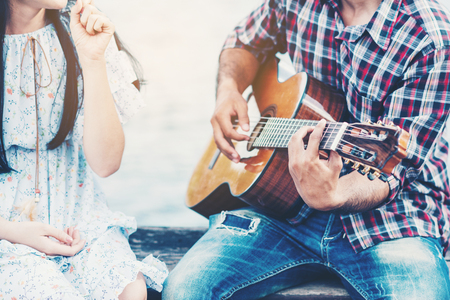 Couple in love with playing guitar at riverの写真素材
