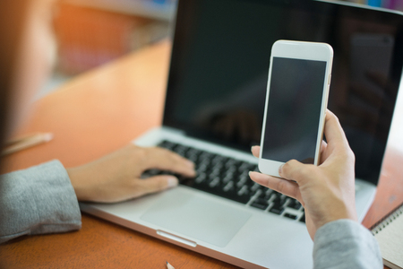 Close up businesswoman in office,beautiful young woman using at smart phone and laptop screenの写真素材