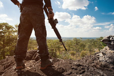 Soldier on the top of a mountain with hand holding gunの写真素材