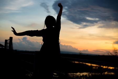 beautiful woman's silhouette at sunset.Portrait of a happy woman freedomの写真素材