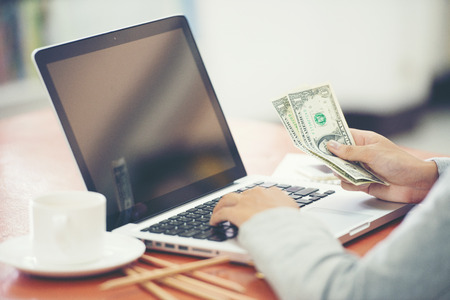 finances, economy and business concept - close up of feman with laptop counting moneyの写真素材