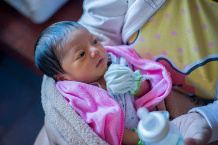 Young mother holding formula drink her little newborn babyの写真素材