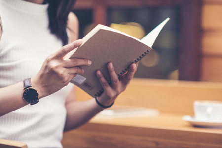Young woman reading a book with cup of coffeeの写真素材