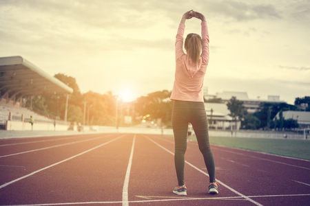 young fitness woman runner stretching legs before run,worm up body in stadiamの写真素材
