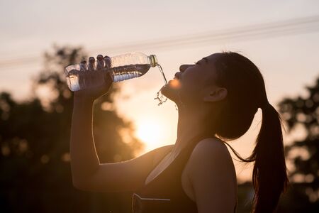 young woman drinking water after joggingの写真素材
