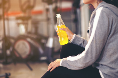 Young beautiful female fitness indoor holding water bottle.healthy conceptの写真素材