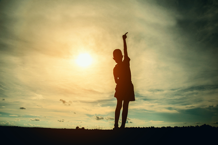 Silhouette of child is jumping with beautiful sunset background.の写真素材
