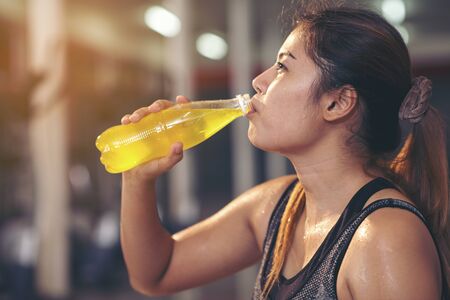 Young beautiful female fitness indoor holding water bottle. healthy conceptの写真素材