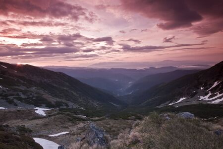 a mountain valley and a red sky with cloudsの写真素材