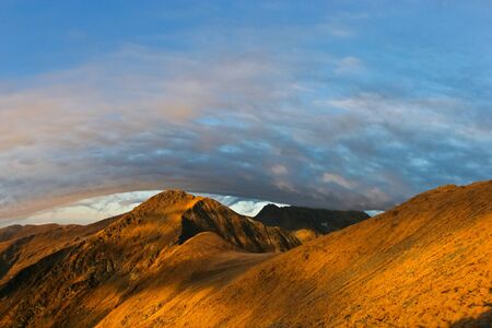 reflection sunrise on a mountain slope under a cloudの写真素材