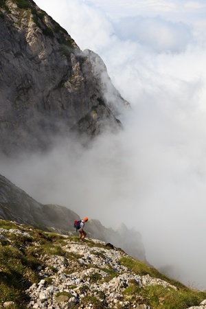 tourist who goes on a mountain valley in fog, Bucegi mountains, Romaniaの写真素材