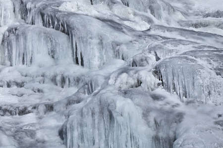 a beautiful waterfall on a mountain river in winterの写真素材