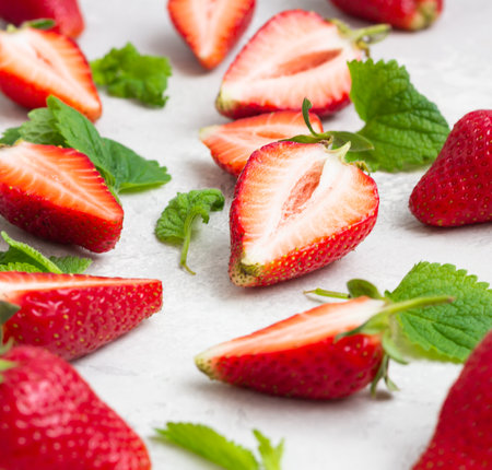 Composition with whole and sliced strawberries and mint leaves on a gray concrete background. Close up.の写真素材