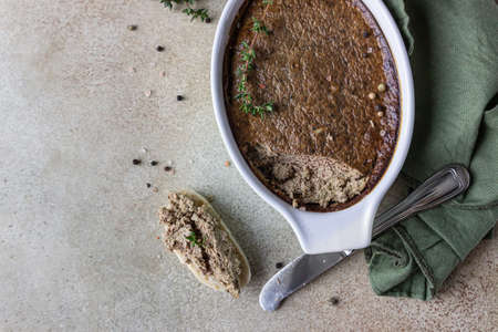 Baked chicken or turkey liver pate or souffle in ceramic mold with thyme, stone background. Top...