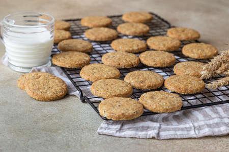 Healthy oatmeal cookies with cereals, seeds and nuts with a cup of milk on concrete background. Diet vegan cookies. Selective focus.の写真素材