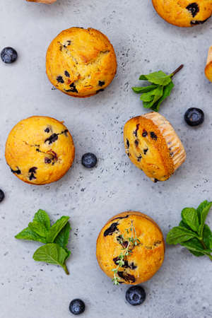 Fresh homemade delicious blueberry muffins decorated with thyme, fresh berries and mint on gray concrete background. Top view.の写真素材