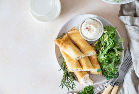 Savory crepes or thin pancakes with chicken served with green salad and bechamel sauce. Meal for...