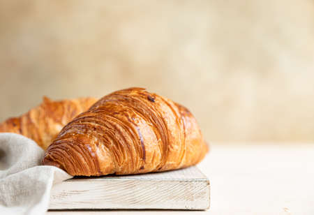 Croissants on wooden cutting board, light concrete background. Selective focus.の写真素材