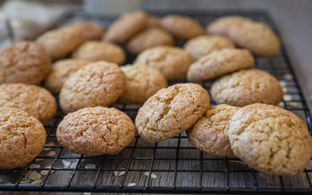 Oatmeal cookies on black metal grille, wooden background. Healthy vegan cookies. Selective focus.